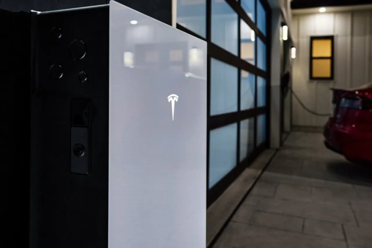 Home garage with an electric vehicle charging next to a Powerwall